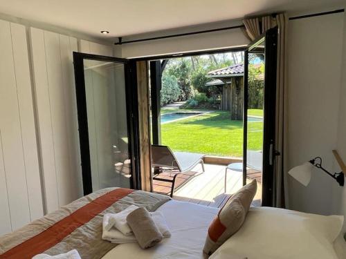 a bedroom with a bed and a sliding glass door at la Villa des Cap - à 400m Océan et Bassin in Cap-Ferret