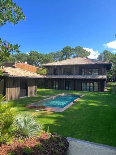 une grande maison avec une piscine dans une cour dans l'établissement la Villa des Cap - à 400m Océan et Bassin, à Cap-Ferret