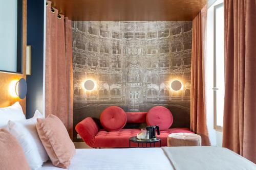 una habitación de hotel con sillas rojas y un mural en la pared en Hotel Sacha, en París