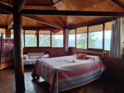 1 dormitorio con 1 cama en una habitación con ventanas en Casa das nuvens en Itatiaia