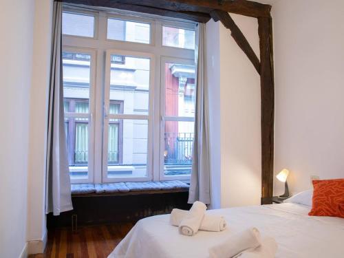 a bedroom with a large window with towels on a bed at Barrenkale Old Town by Next Stop Bilbao in Bilbao