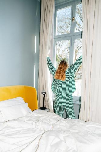 a woman is standing in front of a window at stilwerk Hotel Heimhude in Hamburg