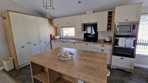 a kitchen with white cabinets and a wooden table at Camber Sands Holiday Park in Camber