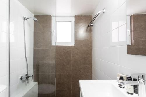 a white bathroom with a shower and a sink at Comfy 1BR Apartment in Ampelokipoi by UPSTREET in Athens