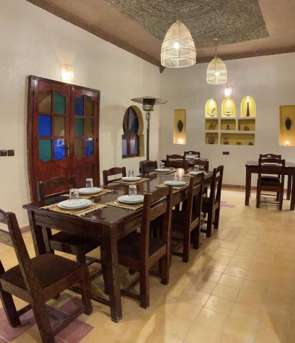 a dining room with a large wooden table and chairs at Riad Dar Poublanc in Merzouga