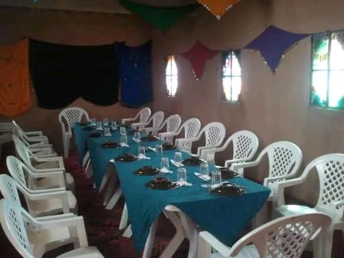 a long table with white chairs and a blue table cloth at désert tours & Hôtel Titanic lac irik in Foum Zguid