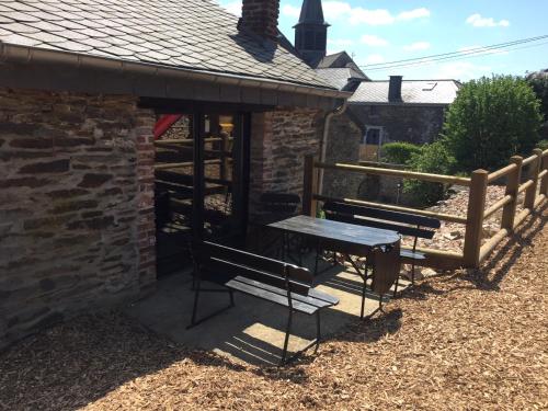 a picnic table and benches in front of a brick building at Gîte écologique 14 pers. à Taverneux - Houffalize in Houffalize