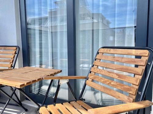 a wooden table and chair on a balcony with a table and a window at Camelia 12 1+1 on Cleopatra with partly seaview in Alanya