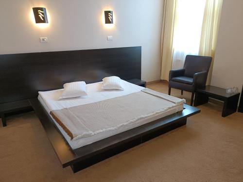 um quarto com uma cama grande e uma cadeira em Hotel Maxim em Arad