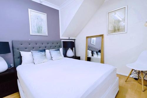 een slaapkamer met een groot wit bed en een spiegel bij Two beds Premier Guest Suite in Castle Hill