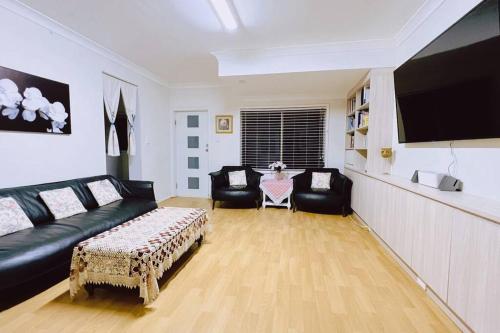 een woonkamer met een zwarte bank en een tv bij Two beds Premier Guest Suite in Castle Hill