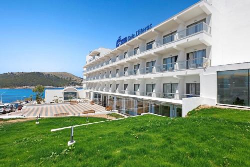 un hôtel avec une pelouse verte en face d'un bâtiment dans l'établissement THB Cala Lliteras, à Cala Ratjada