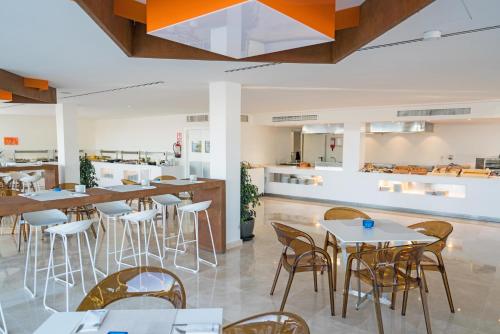 a restaurant with tables and chairs and a kitchen at THB Naeco Ibiza - Adults Only in San Antonio Bay