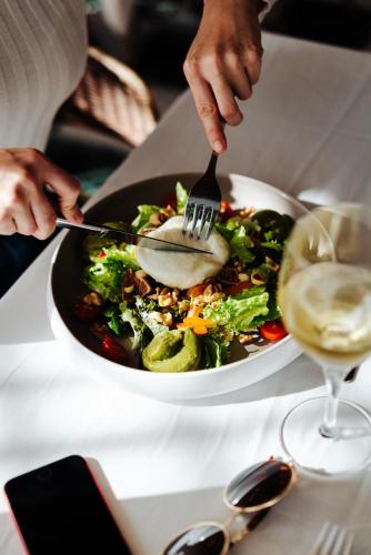 a person eating a salad with a fork and a glass of wine at THB Felip - Adults Only in Porto Cristo