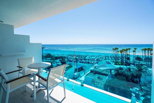 een balkon met uitzicht op een zwembad en de oceaan bij THB Sa Coma Platja in Sa Coma