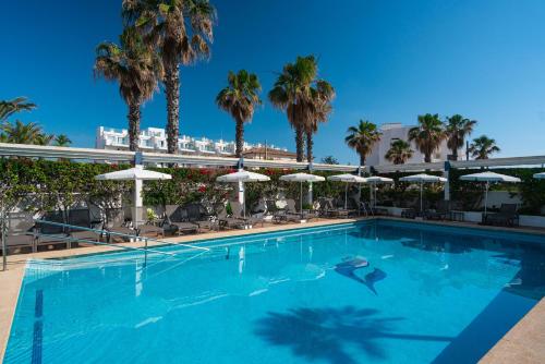 una piscina con palmeras y sombrillas en THB Gran Playa - Adults Only, en Can Picafort