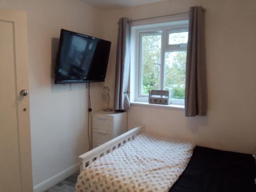 een slaapkamer met een bed en een televisie aan de muur bij Easy Stay in Streatham