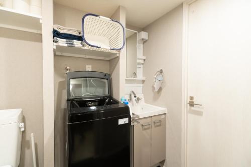 a small kitchen with a black refrigerator and a sink at Caesar House 1Room Shinjuku Shibuya in Tokyo