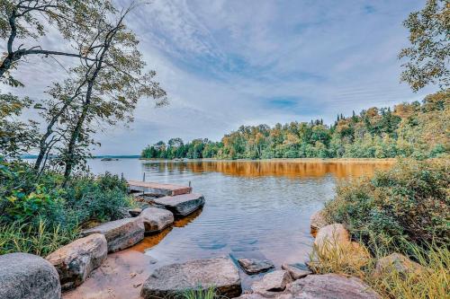 a lake with rocks and trees on the shore at Cordelia with SPA Lake Nominingue 1min in Nominingue
