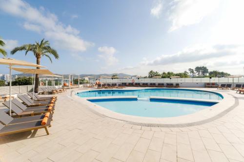 una piscina in un resort con sedie e una palma di THB Ocean Beach a Baia di Sant'Antoni