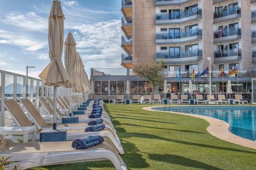 eine Reihe von Liegestühlen mit Sonnenschirmen neben einem Pool in der Unterkunft Hotel THB Gran Bahía in Can Picafort