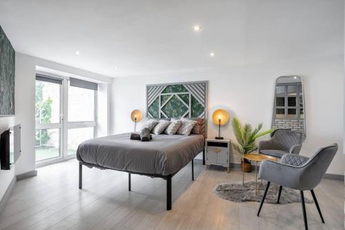 een witte slaapkamer met een bed en een stoel bij 5WJB - Spacious 1 Bed Flat in London in Londen