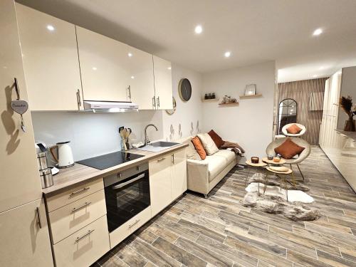 uma cozinha com armários brancos e um sofá num quarto em Appartement Cocooning em Fréjus