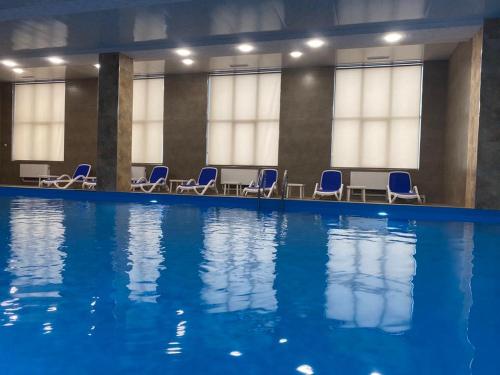 a swimming pool with blue chairs in a building at Uparthotel in Tsaghkadzor