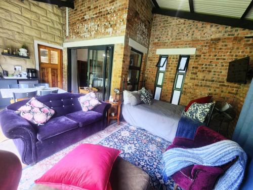 a living room with a purple couch and a brick wall at Naauwpoort View in Clarens