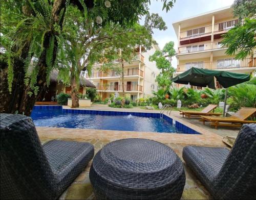 una piscina con sillas y una sombrilla y un edificio en Amor Double Room with Swimming Pool en Boracay