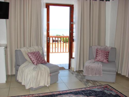 a living room with two chairs and a balcony at A Time And A Place in Plettenberg Bay