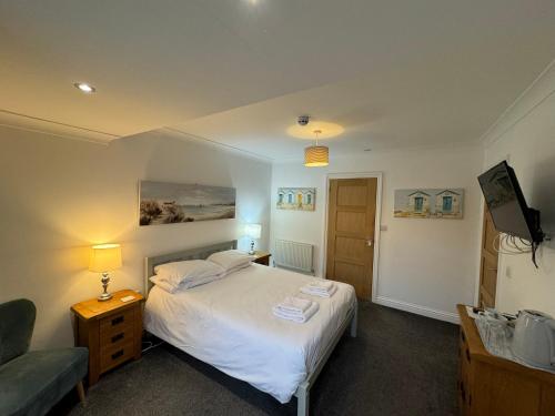 1 dormitorio con 1 cama blanca y 1 silla en The Waves B&B, en Birchington