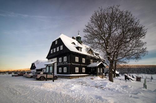 ein großes schwarzes Gebäude mit Schnee drauf in der Unterkunft Panský dům - Jizerka in Jizerka