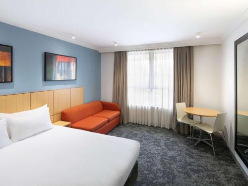 a hotel room with a bed and a couch and a table at Mercure Brisbane Garden City in Brisbane