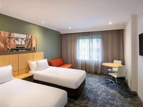 a hotel room with two beds and a table at Mercure Melbourne Southbank in Melbourne