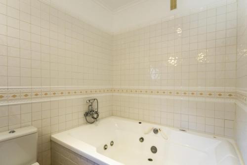 a white bathroom with a tub and a toilet at AGUAIT II - VILLA WITH PRIVATE MOUNTAIN PATH-BEACH APPROX 5 MIN WALKING BEACH,property belong Puerto Pollensa Villas and apartments in Pollença