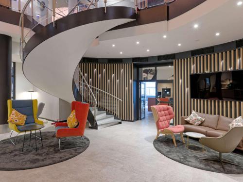 a lobby with chairs and a couch and a staircase at Fora Hotel Hannover by Mercure in Hannover