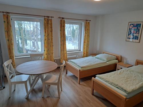 Cette chambre comprend deux lits, une table, une table et des chaises. dans l'établissement Zimmervermietung Hartl, à Barmstedt