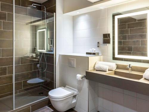 La salle de bains est pourvue de toilettes, d'un lavabo et d'une douche. dans l'établissement Mercure Agen Centre, à Agen