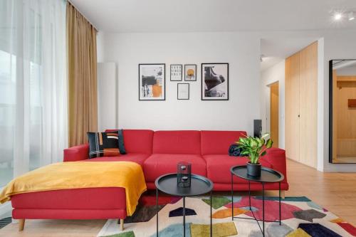 ein Wohnzimmer mit einem roten Sofa und 2 Tischen in der Unterkunft On the Danube, city center, free parking in Bratislava