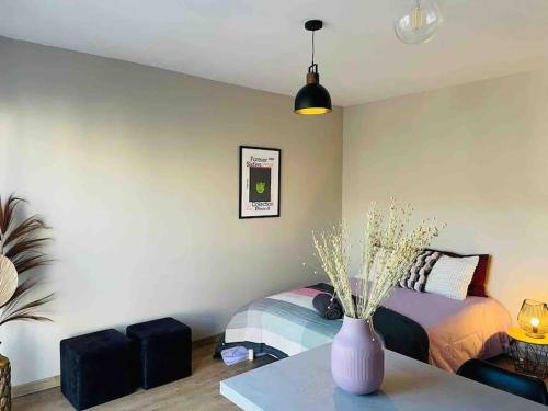 a bedroom with a bed and a vase on a table at Au calme de la Gaité in Saint-Jacques-de-la-Lande