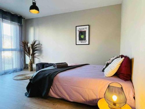 ein Schlafzimmer mit einem großen Bett und einer Lampe in der Unterkunft Au calme de la Gaité in Saint-Jacques-de-la-Lande