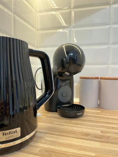 a black mixer sitting on a counter next to cups at Apartament Rubinowy in Toruń