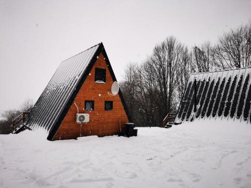 a large brick barn with snow on the ground at Rock Valley Cabins A-frame in Ibăneşti