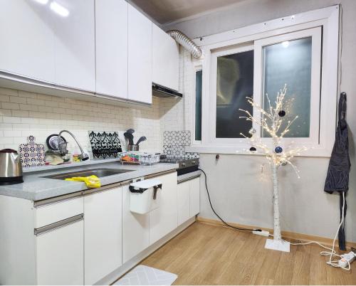a white kitchen with a tree in the middle of it at Stay in North Seoul in Seoul