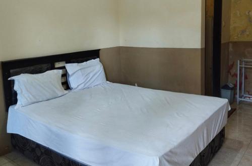 a bedroom with a large bed with white sheets and pillows at OYO Life 93265 Kos Cendana Seruni Raya in Mataram
