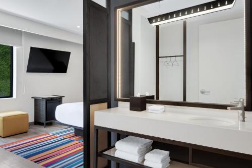 a bathroom with a sink and a mirror at Aloft Santo Domingo Piantini in Santo Domingo