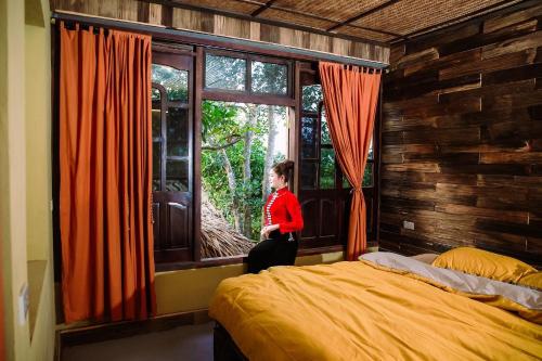 a child sitting in a window in a bedroom at Muonglo Farmstay in Yên Bái