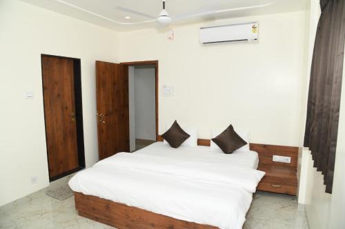 a bedroom with a large white bed with black pillows at Hotel Apex, Akkalkot in Akalkot
