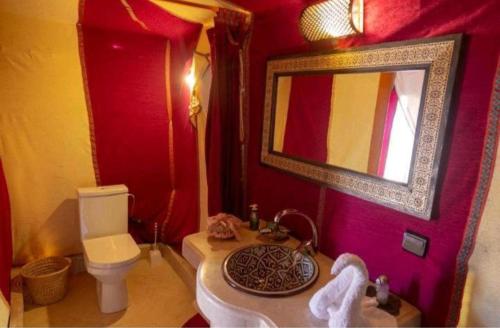 bagno con lavandino, servizi igienici e specchio di Merzouga Luxury Camp a Merzouga